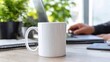 © Bagas - Bright workspace person types on laptop near a white mug, with potted plants providing a fresh backdrop on a light wooden desk