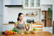 © laddawan - Woman Preparing Healthy Meal in Kitchen, Fit Woman Making Smoothie and salad with Fresh Ingredients at home. Active healthy lifestyle, clean eating concept