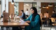 © Disiplin - A young woman in a teal abaya works on documents at a modern co-working space, surrounded by other professionals.