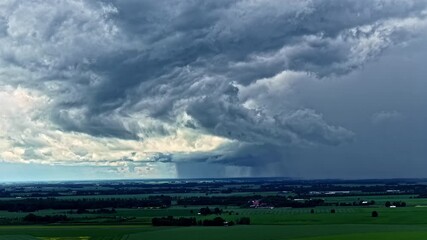 Wall Mural - dramatic rainstorm seen approaching over rural farmland under swirling clouds