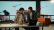 © Videophilia - Architects discussing blueprint using laptop in office overlooking construction site