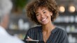 © Jane_S - Smiling african female adult with curly hair engaging in conversation indoors