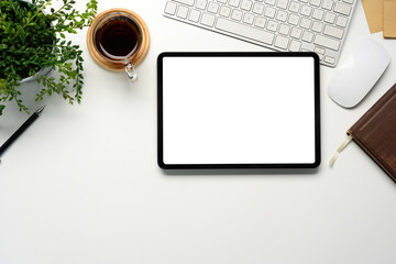 Wall Mural - top view of office desk with blank tablet screen, coffee cup, and green plant