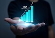 © RaCreative - Person s outstretched hand holding glowing blue bar graph with rising trend line
