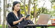 © banphote - Portrait of young girl using laptop and a phone while sitting in the park