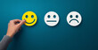 © Prostock-studio - Hand choose the happy smile icon over blue background, panorama, copy space. Customer service evaluation and satisfaction survey concept