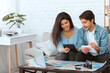 © Prostock-studio - Plan finances. Couple preparing for vacation and calculating expenses, using laptop and map, free space