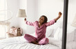 © Prostock-studio - Happy Well-Slept Black Female Stretching Hands After Healthy Sleep Sitting On Bed In Modern Bedroom At Home, Wearing Pajamas. Cheerful Lady Enjoying Weekend Morning Concept