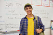 © Rido - Smiling cool teen student looking at camera in classroom