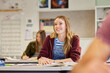 © Rido - Smiling female teenager listening to teacher in classroom