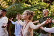 © Rido - Young woman meditating with a group of diverse people outdoor