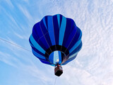 Colorful blue hot air balloon rising into the sky during a summer festival. Clear blue sky.  View from under the balloon