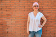 © TrueShot | Westend61 - Mature woman with hand on hip standing in front of brick wall