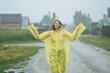 © TrueShot | Westend61 - Carefree woman wearing raincoat and enjoying rain on road