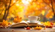 © Yelloone - A cup of coffee rests on an open book surrounded by vibrant autumn leaves with a warm, glowing background.