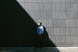 © TrueShot | Westend61 - Young businessman standing in front of a grey wall looking up