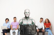 © New Africa - Robot with bag against group of people waiting for job interview, selective focus. Artificial intelligence in recruitment