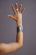 © Seventyfour - Cropped vertical shot of Caucasian young adult woman raising left arm with open hand, displaying silver ring and wide metallic bracelet against plain background during fashion photoshoot