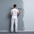 © Ouzhan - A painter, with his back to the viewer, painting a wall with a roller, in white overall outfit. The wall is being painted gray