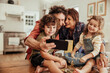 © Marko Geber - Happy young family taking a selfie with a smartphone while being messy and baking with flour at home in the kitchen