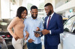 © Prostock-studio - Handsome Car Seller Showing Purchasing Details On Digital Tablet To Young Black Couple In Dealership Center, Happy African American Spouses Buying New Vehicle In Automobile Showroom, Closeup