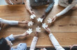 © Prostock-studio - Startup and teamwork concept, top view of creative multiracial team sitting at table and putting together puzzle pieces