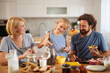 © Stockphotodirectors - A family gathers in their bright kitchen, with a girl measuring ingredients, while her parents smile and share food, creating a warm and joyful breakfast moment.