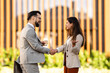 © Zoran Jesic - Business people shaking hands outdoors holding coffee and smiling