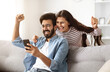 © Prostock-studio - Great news. Excited happy millennial indian man and woman looking at phone screen, clenching fists and exclaiming. Emotional eastern couple celebrating success, gambling online. Cashback