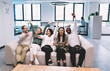 © BullRun - Happy multicultural team celebrating together on couch, cheering with raised hands like fans at game, capturing joy, collaboration and emotional unity in office relaxation zone