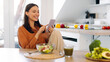© Home-stock - Lady blogger savoring fresh salad while using her cellphone in kitchen, writing post or texting online. Healthy lifestyle and digital connectivity
