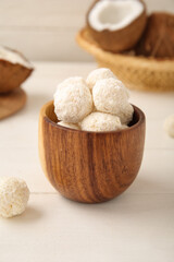 Wall Mural - Wooden bowl with tasty coconut candies on white table