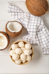 Wall Mural - Bowl with white chocolate candies and coconuts on light wooden table