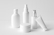 © Mostafizur - Set of five clean, white skincare and cosmetic packaging bottles, including a cream jar, spray bottle, and pump bottle, displayed on a neutral background, facial makeup skincare Background