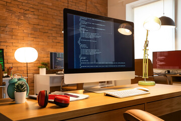 Wall Mural - programmer's desk with computer and glowing lamps in office