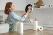 © Pixel-Shot - Young woman with rolls of paper towels cleaning frying pan near table in kitchen