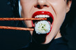 © VICHIZH - A stylish woman with red lips holding sushi with chopsticks, showcasing a vibrant eating experience with a modern touch.