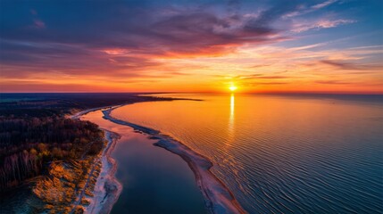 Wall Mural - Vibrant hues of orange and purple fill the sky as the sun sets over a tranquil lake, casting a beautiful reflection on the water and enhancing the peaceful shoreline.