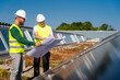 © BusinessClass by W61 - Two technicians studying plan on the roof of a company building with solar panels