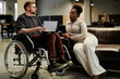 © BusinessClass by W61 - Businesswoman listening to disabled colleague on wheelchair at office