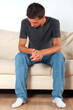 © romikmk - sad young man sits on a sofa with his head down