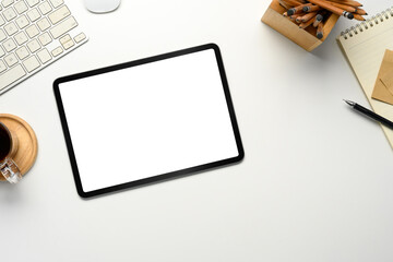 Wall Mural - top view of digital tablet on white desk with office supplies, coffee cup, and stationery