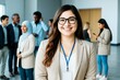 © Pixels Hunter - Confident young woman in business attire smiling at networking event with diverse professionals in background in bright office space.