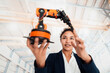 © BusinessClass by W61 - Smiling young businesswoman examining robotic arm in factory