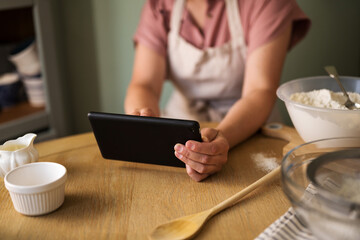 Woman using a digital tablet in the kitchen for finding recipe