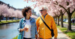 ©  VladaToday - Smiling couple walking under blooming cherry blossom trees in a park setting with copy space