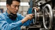 © Olesya - Concentrated asian man in blue uniform operating metal machinery, adjusting controls. Industrial manufacturing, factory production concept.