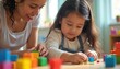 © Maryna - Young Hispanic girl, teacher collaborate building with colorful blocks in bright kindergarten classroom. Focused attention, collaborative spirit, playful learning environment encourages development,
