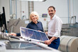© BusinessClass by W61 - Smiling businessman holding solar panel standing by businesswoman in industry