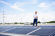 © BusinessClass by W61 - Businessman using smart phone standing by solar panels on rooftop